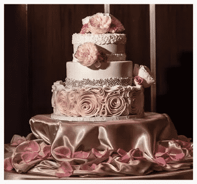 A White and pink wedding cake covered in flowers.