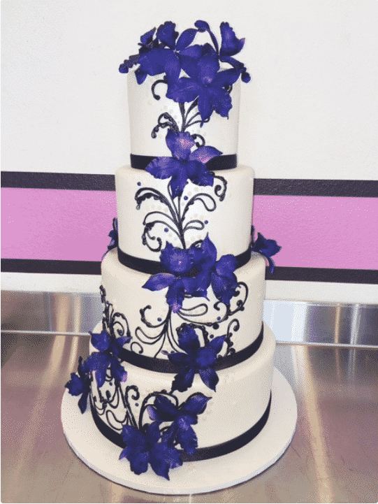 A white and black wedding cake decorated in bright purple flowers.