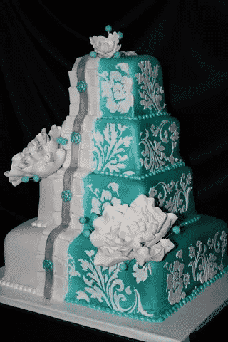 A teal and white wedding cake with white flowers.