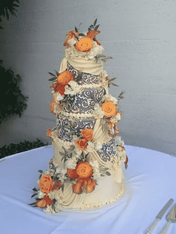 A wedding cake with purple and white decals and orange flowers.